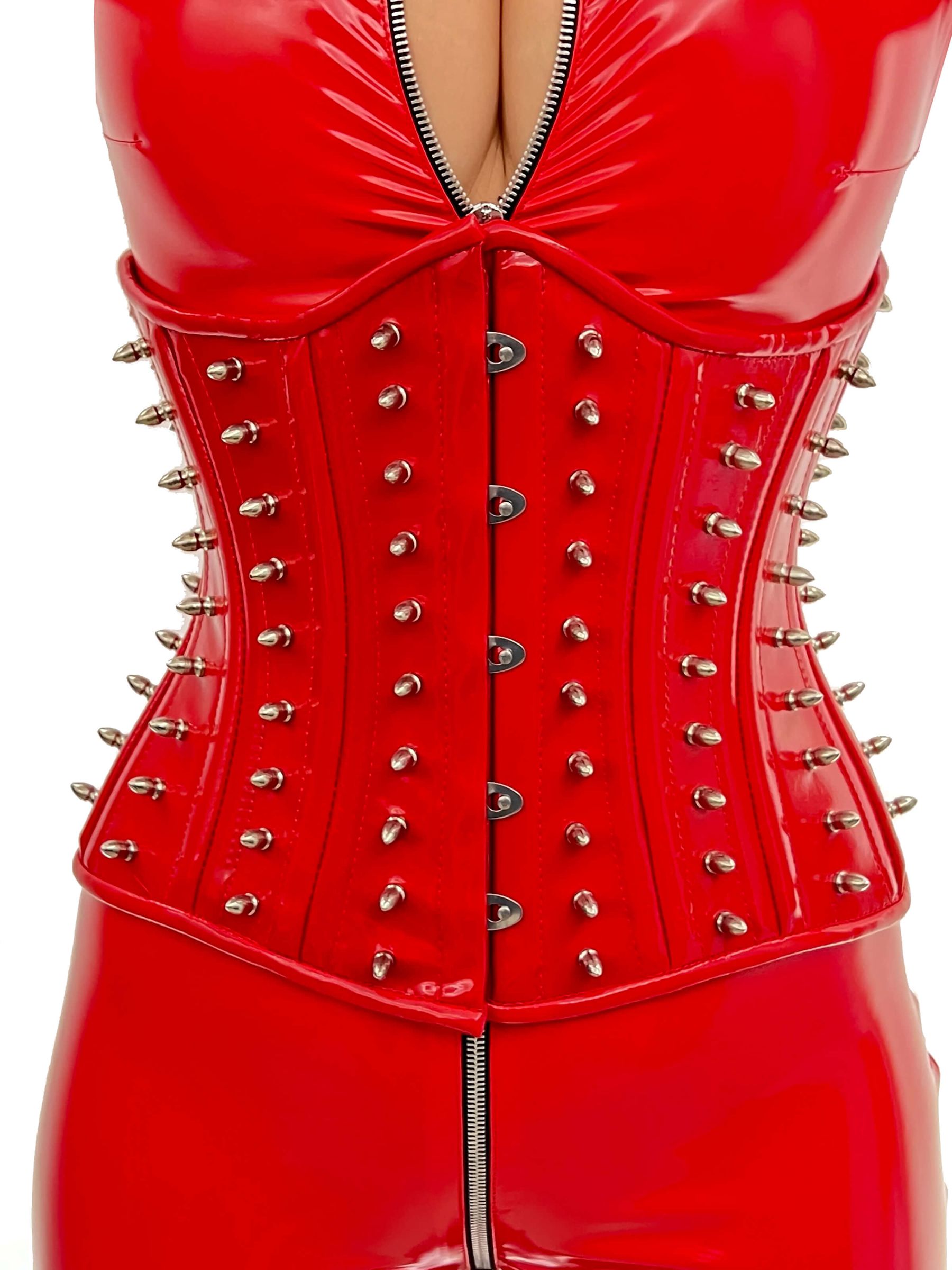 Rotes Lackkorsett Spike mit silbernen Nieten, figurformend und auffällig, getragen über einem glänzenden Lackanzug